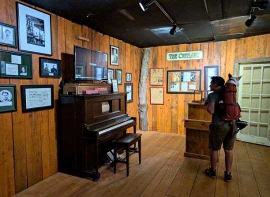 Man with dog in backpack carrier looking around The Outlaw room at Gangster Museum of America