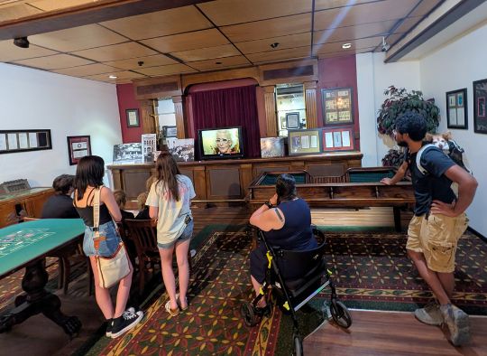 group including dog sleeping in backpack watching a video during the Gangster Museum tour