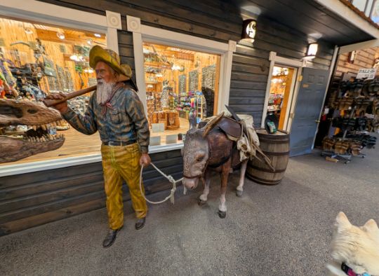 Dog walking by a statue of a man walking a donkey
