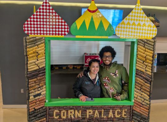 Two people standing in mini Corn Palace photo op